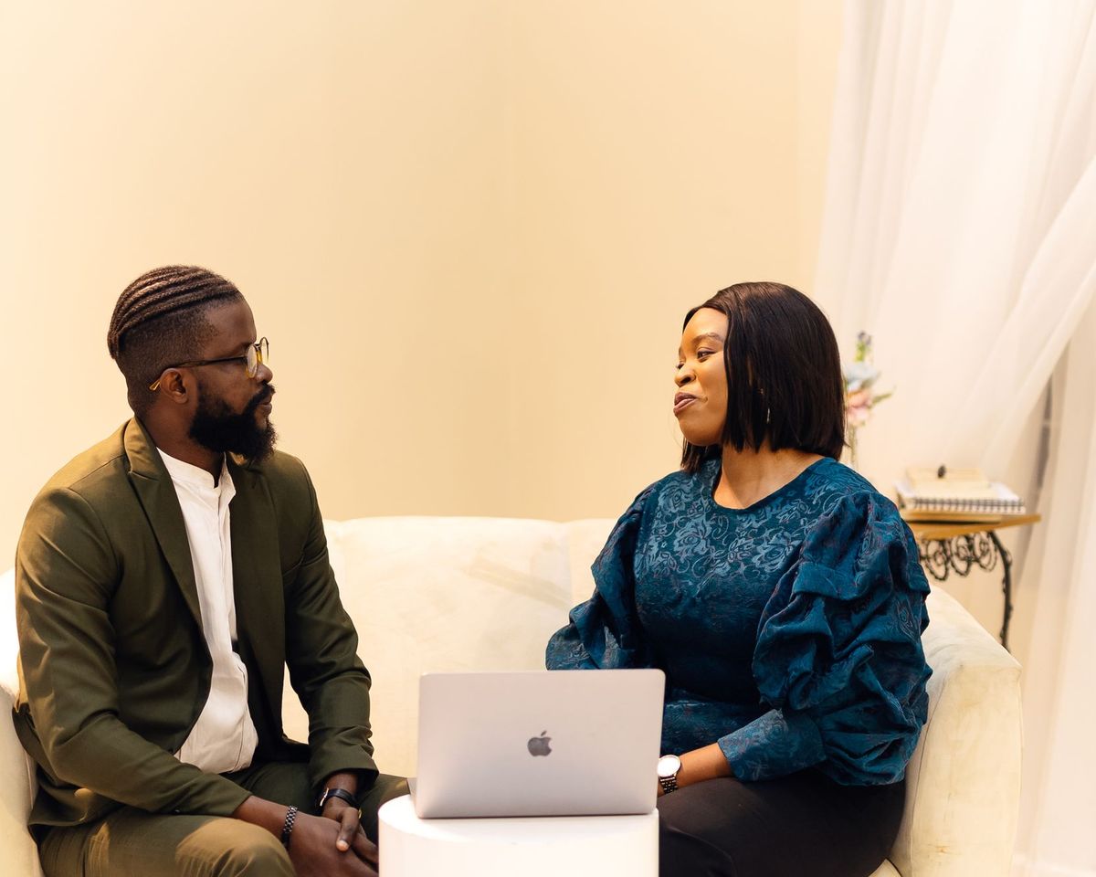 Two people in conversation over a laptop in a bright room